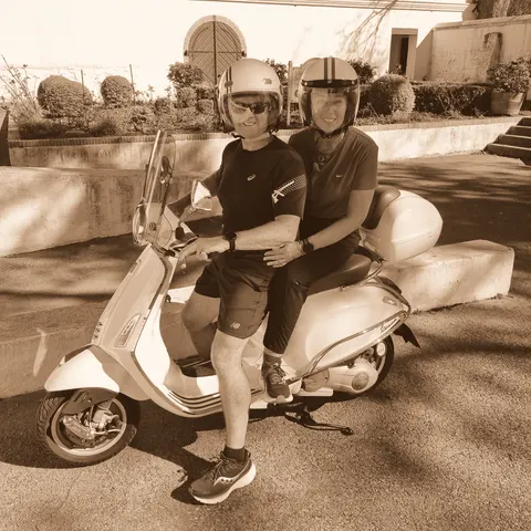 Sharing a scooter in helmets on a village lane