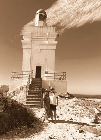Small figures at the foot of a lighthouse, sky filling the frame