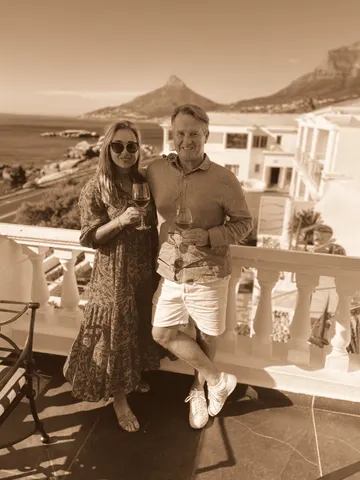On a balcony above a bay, mountains behind